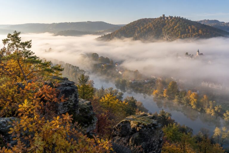 Ranní mlha ležící v údolí pod slunečným hřebenem